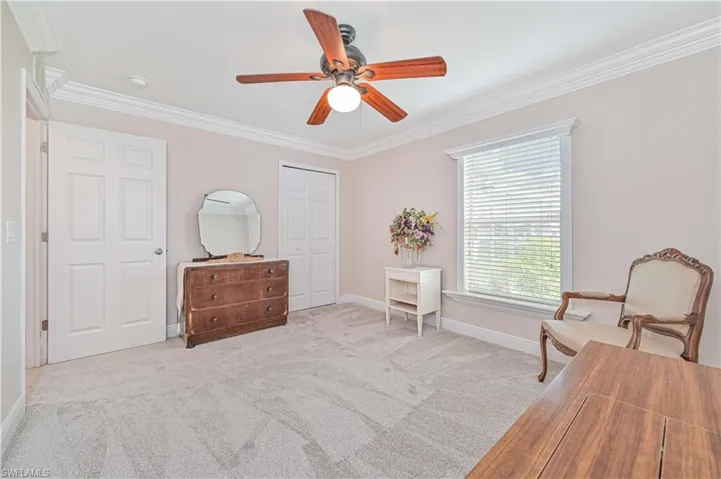 Living area featuring ceiling fan, ornamental molding, and light carpet
