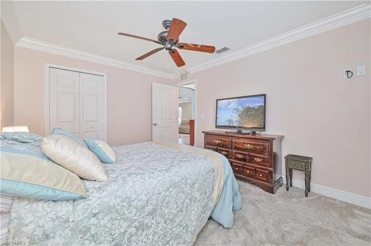 Carpeted bedroom featuring ceiling fan, a closet, and crown molding