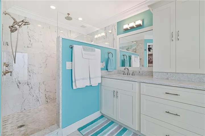 Bathroom featuring vanity, tiled shower, and ornamental molding