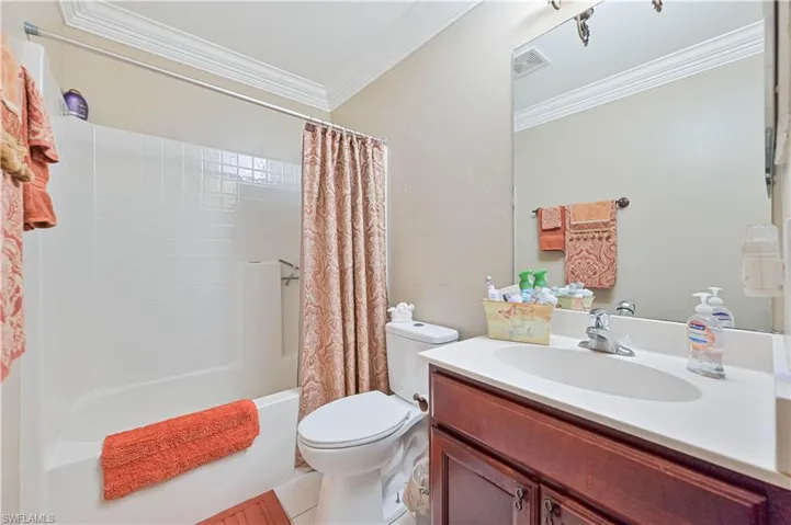 Full bathroom featuring shower / bath combination with curtain, tile patterned floors, vanity, crown molding, and toilet