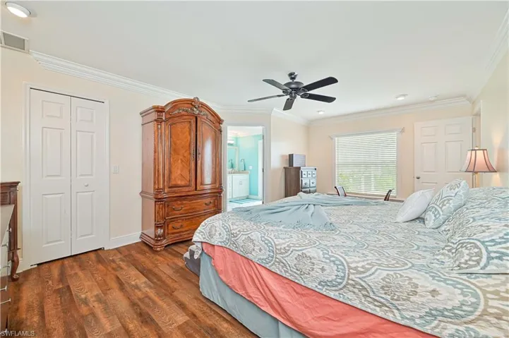 Bedroom with ceiling fan, crown molding, a closet, and dark hardwood / wood-style flooring