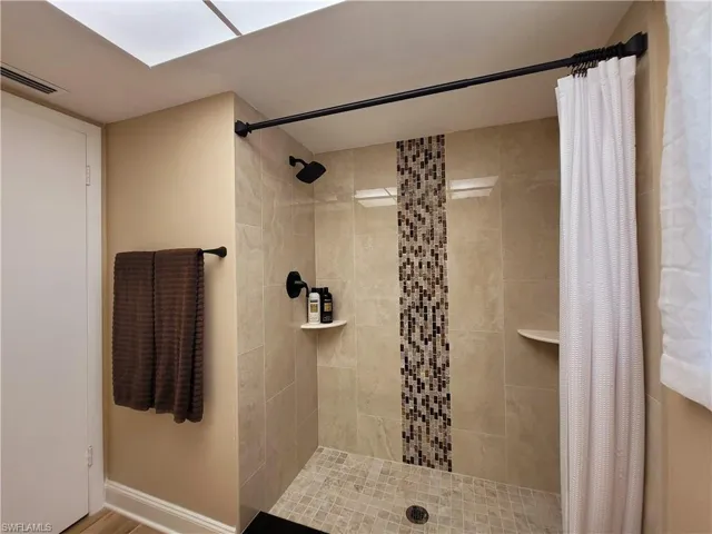 Shower with large format wall tiling, mosaic tile accent, and a tiled shower pan