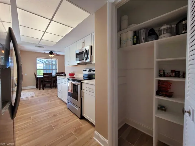 Kitchen featuring white cabinetry with silver-tone hardware, stainless steel appliances, and a pantry with built-in shelving