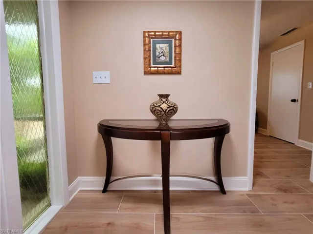 Entryway featuring wood-finish tile flooring and a decorative sidelight with patterned glass