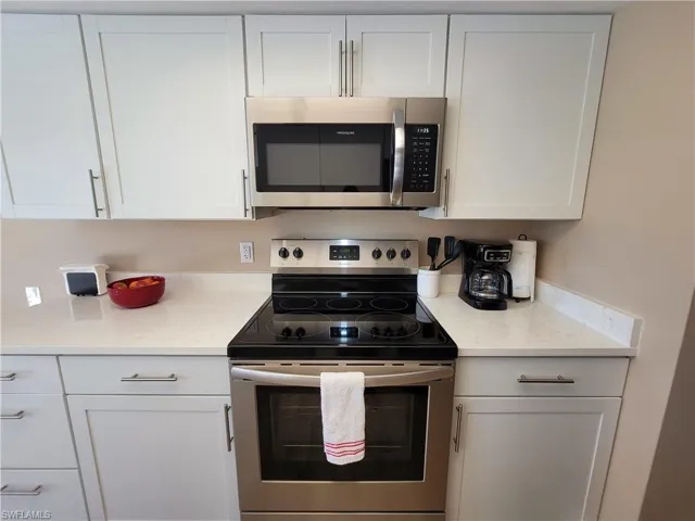 Contemporary kitchen featuring white shaker-style cabinetry, stainless steel appliances, and light-toned countertops