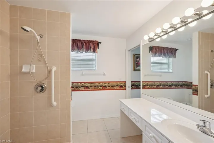 Guest bathroom with healthy amount of natural light, vanity, and a tile shower