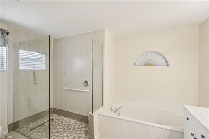 Bathroom with a jetted tub, vanity, and a tile shower