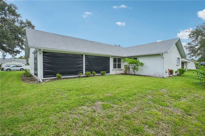 Back of property featuring a lawn and stucco siding