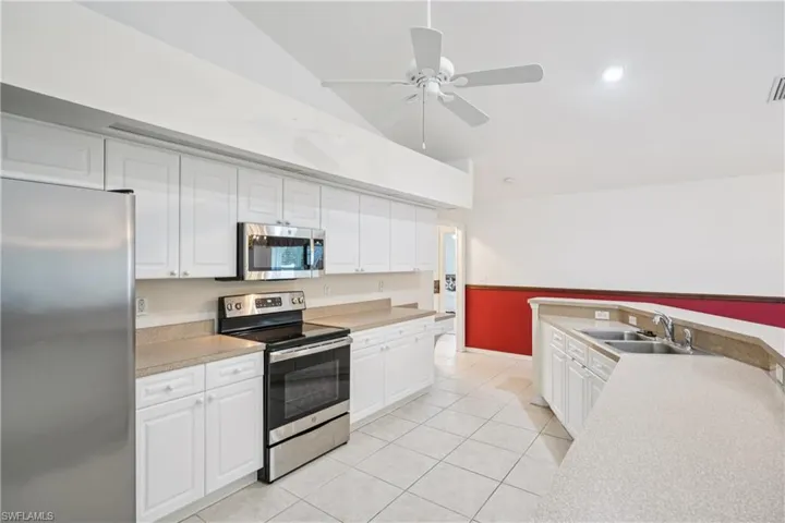 Kitchen featuring stainless steel appliances, white cabinetry, light tile patterned floors, a ceiling fan, and light countertops
