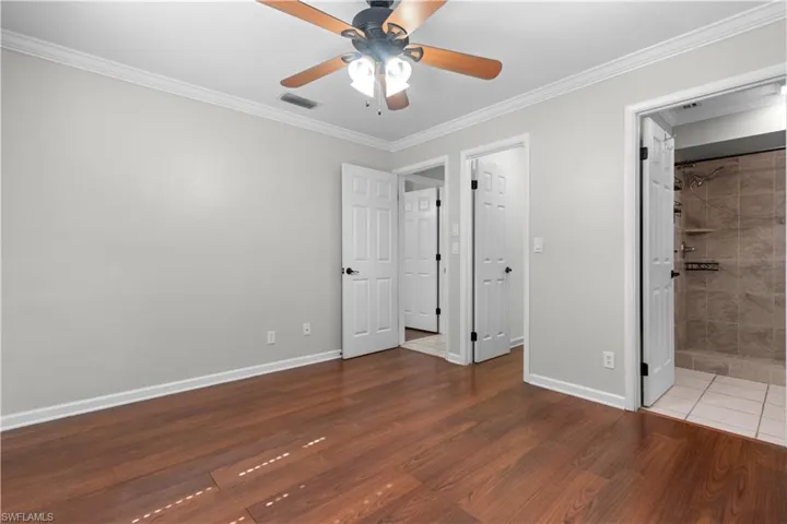 Primary ensuite featuring wood-finish flooring, light gray walls, and white crown molding