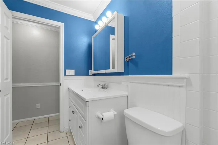 Guest bathroom with a single vanity, white cabinetry, a top-mounted sink, and a mirrored medicine cabinet