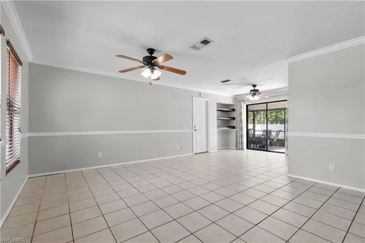 Open floor plan with plenty of natural light, tile flooring, white chair rail molding, and crown molding