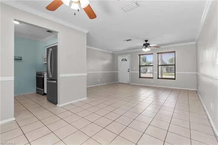 Open-concept living space featuring neutral-toned walls with chair rail molding, and tile flooring.