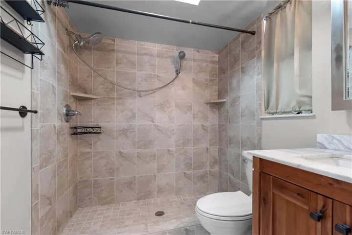 Tiled shower enclosure featuring a handheld showerhead and built-in shelving