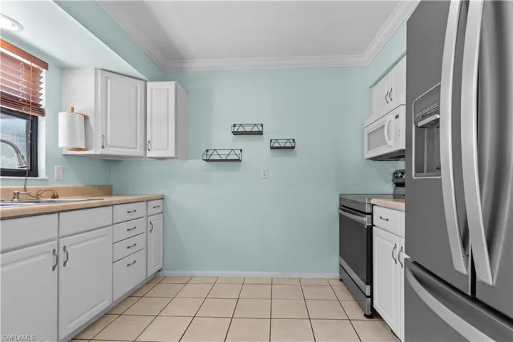 Kitchen featuring white cabinetry, light-toned countertops, and square floor tiles