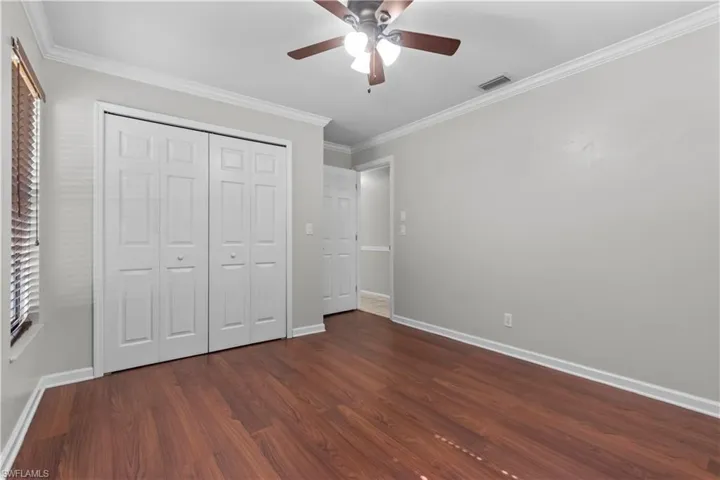 Third bedroom featuring wood-finish flooring, light grey painted walls, white crown molding, and white baseboards