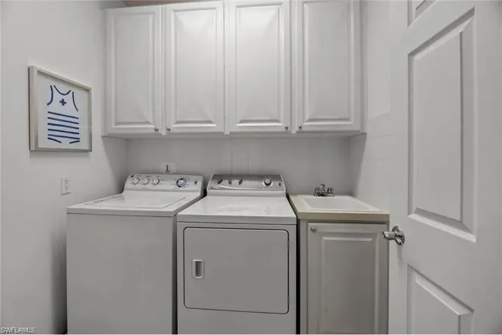 Laundry room featuring a top-load washing machine, a front-load dryer, and a utility sink with white cabinetry