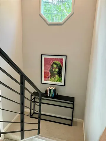 This property features a stairwell with a contemporary black metal railing and neutral-toned carpeting