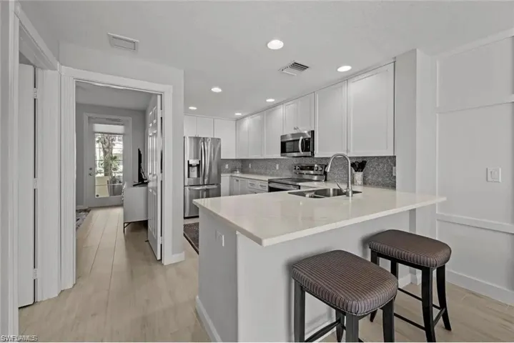 The kitchen features stainless steel appliances, white cabinetry, a light-colored countertop, and recessed lighting