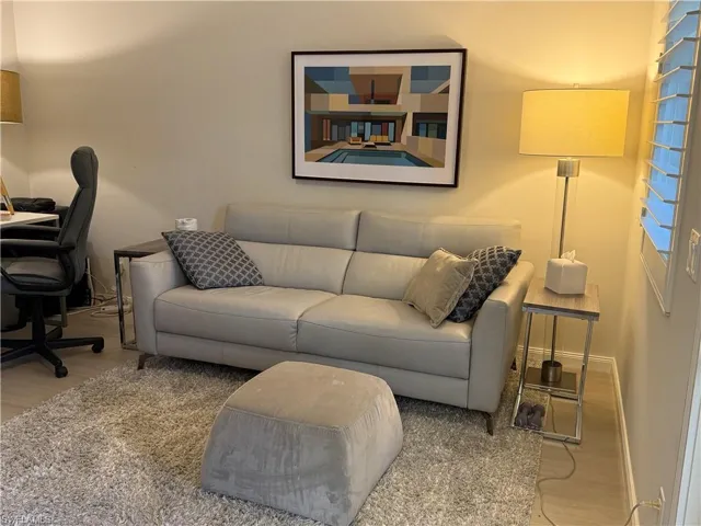 Living area featuring light-colored walls, a textured area rug, and a wall-mounted artwork