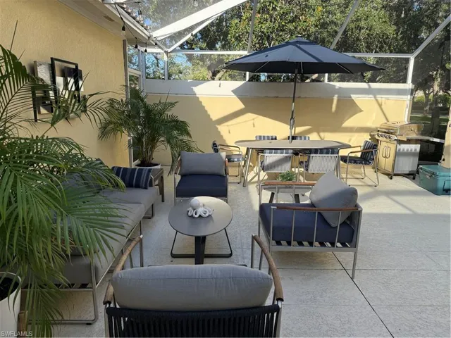 Spacious screened patio featuring a dining area with an umbrella, and a separate seating area with lounge chairs and a sofa