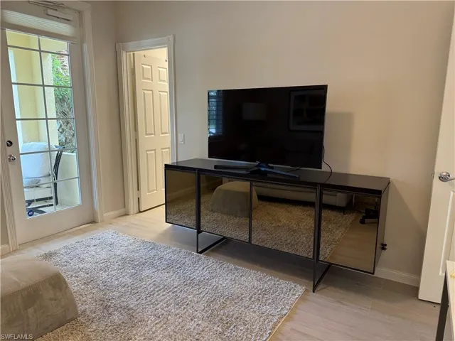 Living area featuring a glass-paned door opening to an outdoor patio, light-colored flooring, and neutral wall tones