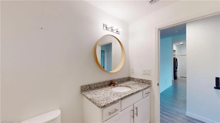 Bathroom featuring washer / clothes dryer, vanity, toilet, and hardwood / wood-style flooring