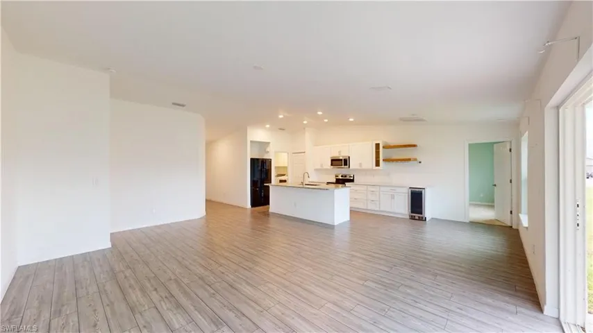 Unfurnished living room with sink, wine cooler, and light hardwood / wood-style flooring