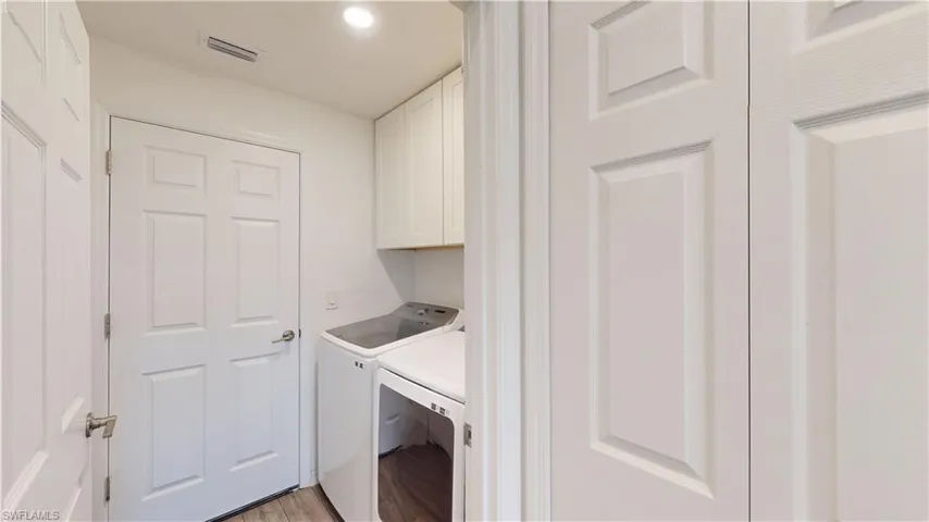 Laundry room with washing machine and dryer, cabinets, and light hardwood / wood-style flooring
