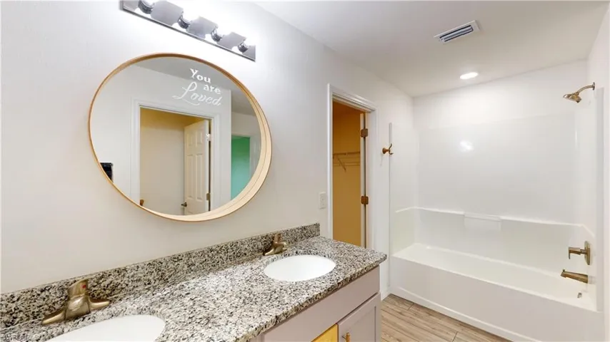 Bathroom with vanity, washtub / shower combination, and hardwood / wood-style flooring