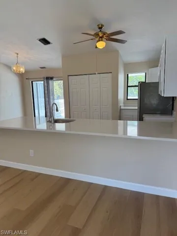 Kitchen with a peninsula, white cabinets, healthy amount of natural light, and light stone countertops