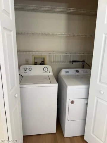 Laundry room with wood finished floors and washing machine and dryer