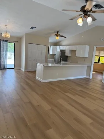 Kitchen with white cabinetry, a peninsula, open floor plan, fridge, and light wood-type flooring