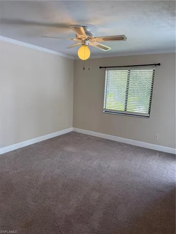 Spare room with crown molding, light carpet, and ceiling fan