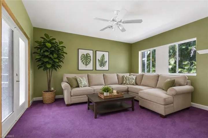 Staged Spacious living Bedroom that goes out to the pool, featuring vibrant purple carpeting, olive green walls, and white ceiling