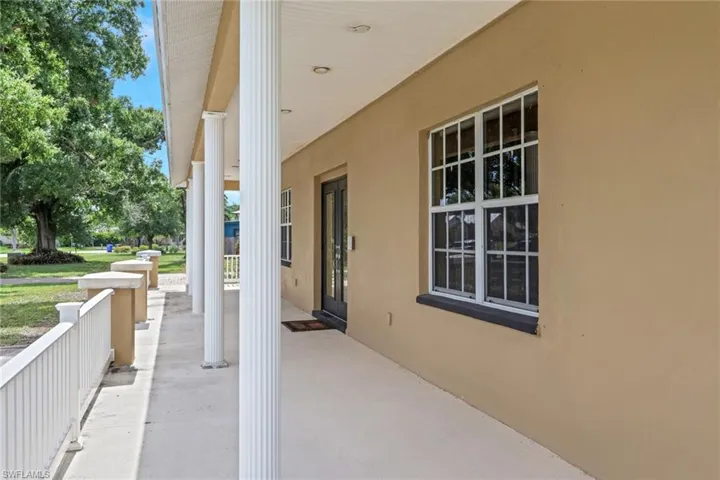Exterior facade featuring a covered porch with white fluted columns, a concrete walkway, and a white railing system