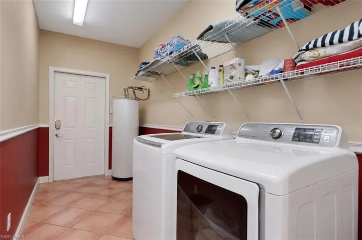 Laundry room featuring tiled flooring, a white paneled door, and two rows of built-in wire shelving