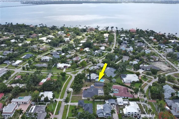 Aerial perspective showcasing a residential neighborhood with surrounding water and a distant bridge