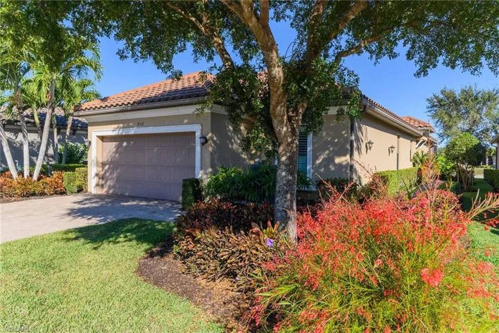 View of front facade with an attached garage, stucco siding, driveway, and a tiled roof