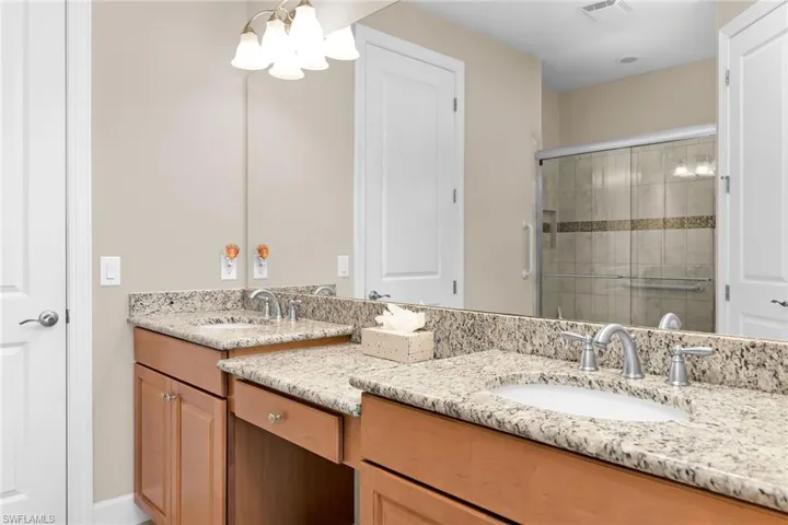 Bathroom featuring a stall shower, double vanity, and a chandelier