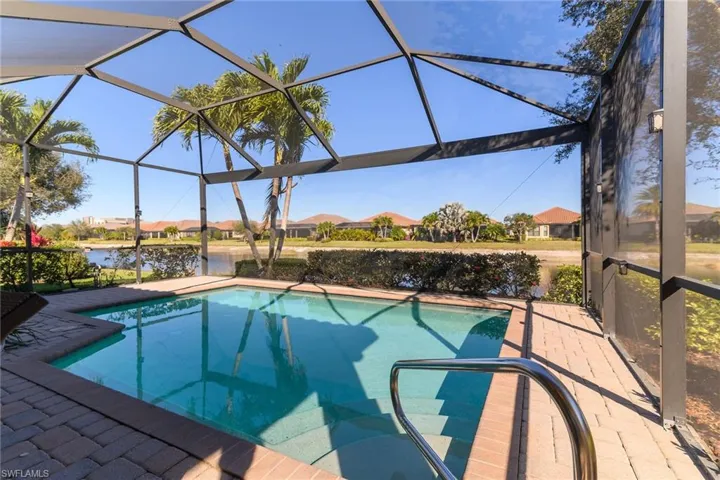 Outdoor pool with glass enclosure, a residential view, a sunroom, a water view, and a patio area