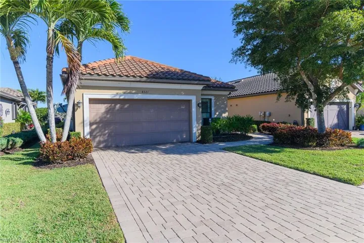 Mediterranean / spanish-style house featuring decorative driveway, a tiled roof, a front lawn, an attached garage, and stucco siding