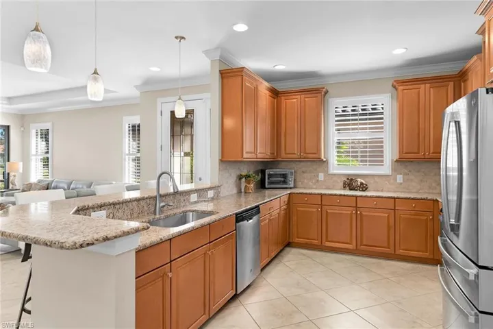Kitchen featuring crown molding, light stone countertops, open floor plan, a breakfast bar area, and decorative backsplash