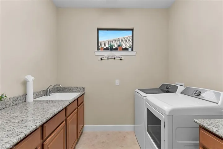 Laundry area with washing machine and clothes dryer, light tile patterned flooring, and cabinet space