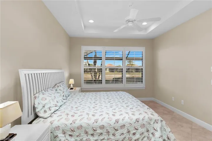 Bedroom with a tray ceiling, ceiling fan, recessed lighting, and light tile patterned floors
