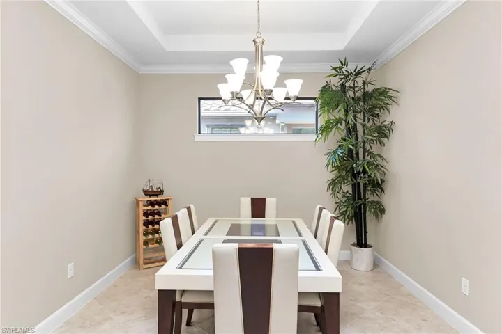Dining area featuring ornamental molding, a raised ceiling, and a chandelier