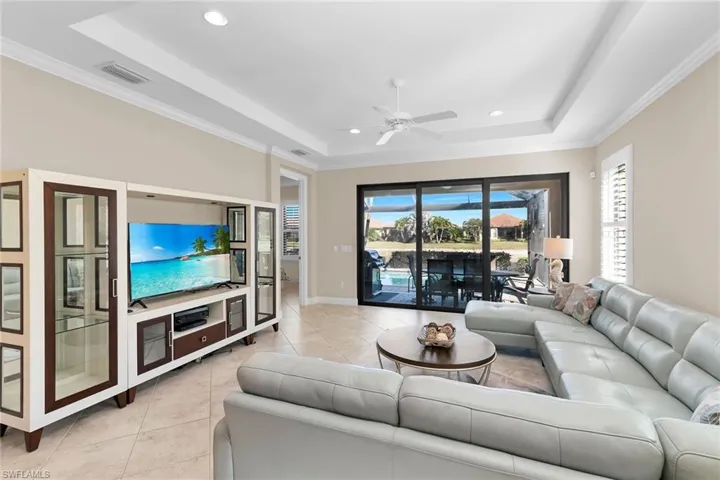 Living area featuring crown molding, ceiling fan, a tray ceiling, light tile patterned floors, and recessed lighting