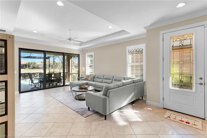 Living room featuring a ceiling fan, a raised ceiling, recessed lighting, and light tile patterned floors