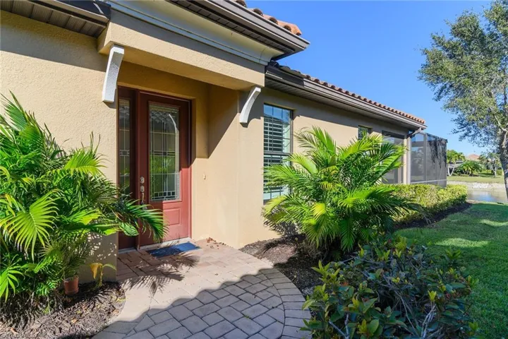 Doorway to property featuring stucco siding, a tiled roof, and a lawn