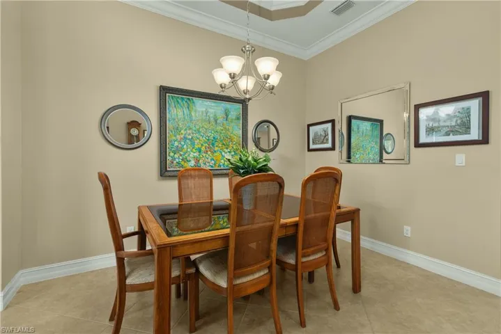 Dining area with an inviting chandelier, crown molding, and light tile patterned flooring